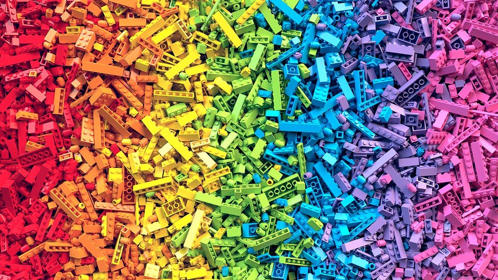 An infinite amount of Lego pieces divided by color. From left to right: red, orange, yellow, green, turquoise, lilac, pink.